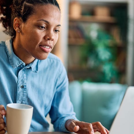Woman in Edmonton attending an online Spanish lesson with Berlitz Canada from her laptop while drinking a cup of tea
