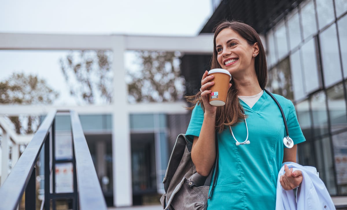 Woman in nurse clothes drinking coffee and smiling after her language training for healtcare workers with Berlitz Canada