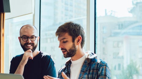 Student holding a laptop in hi shands and talking to his instructor during a private language lesson with Berlitz Canada