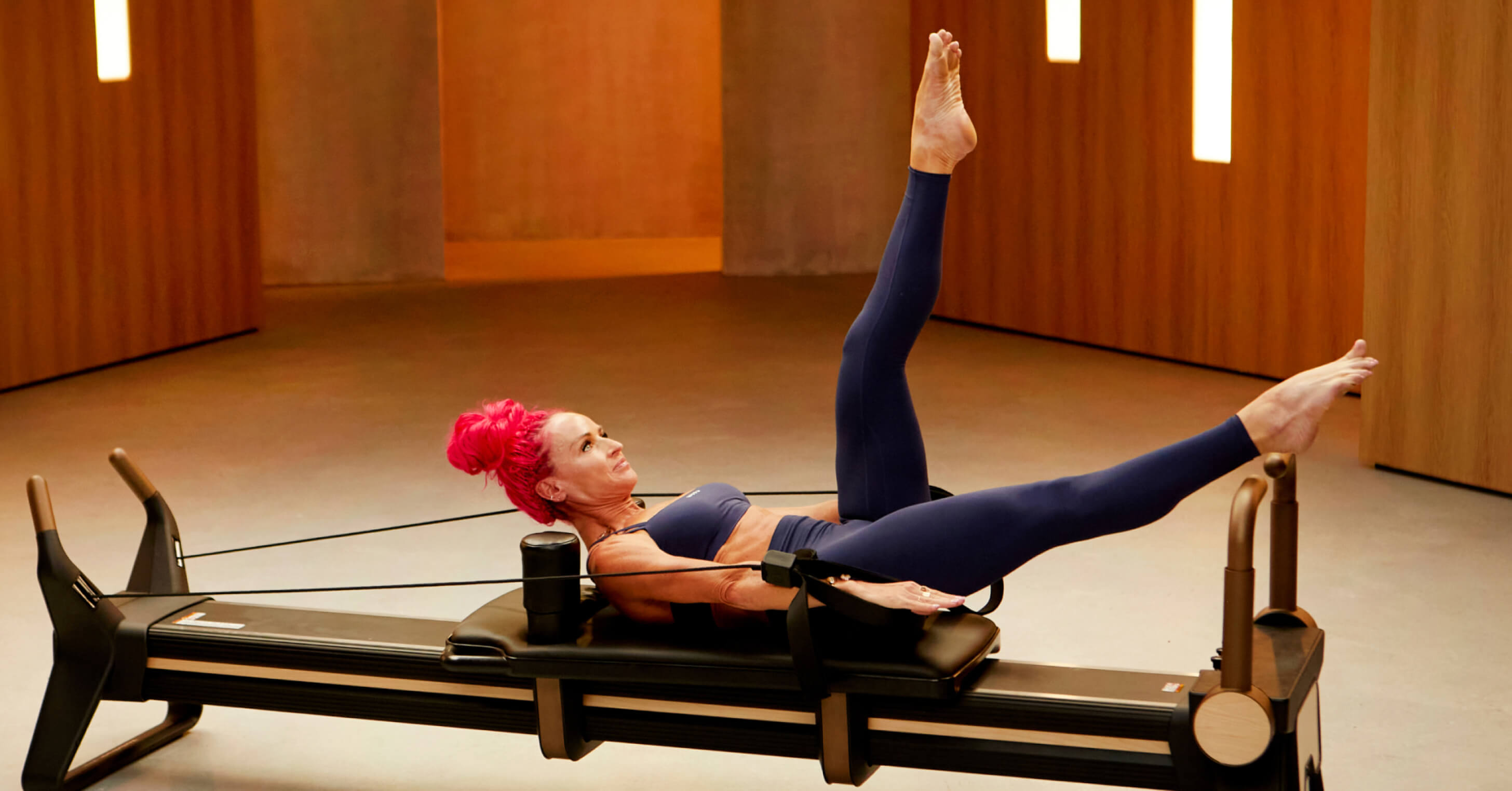 Ashley Paulson demonstrates a supine leg extension from the Strong Stride Series, a 7-workout intermediate reformer Pilates program for stride strength.