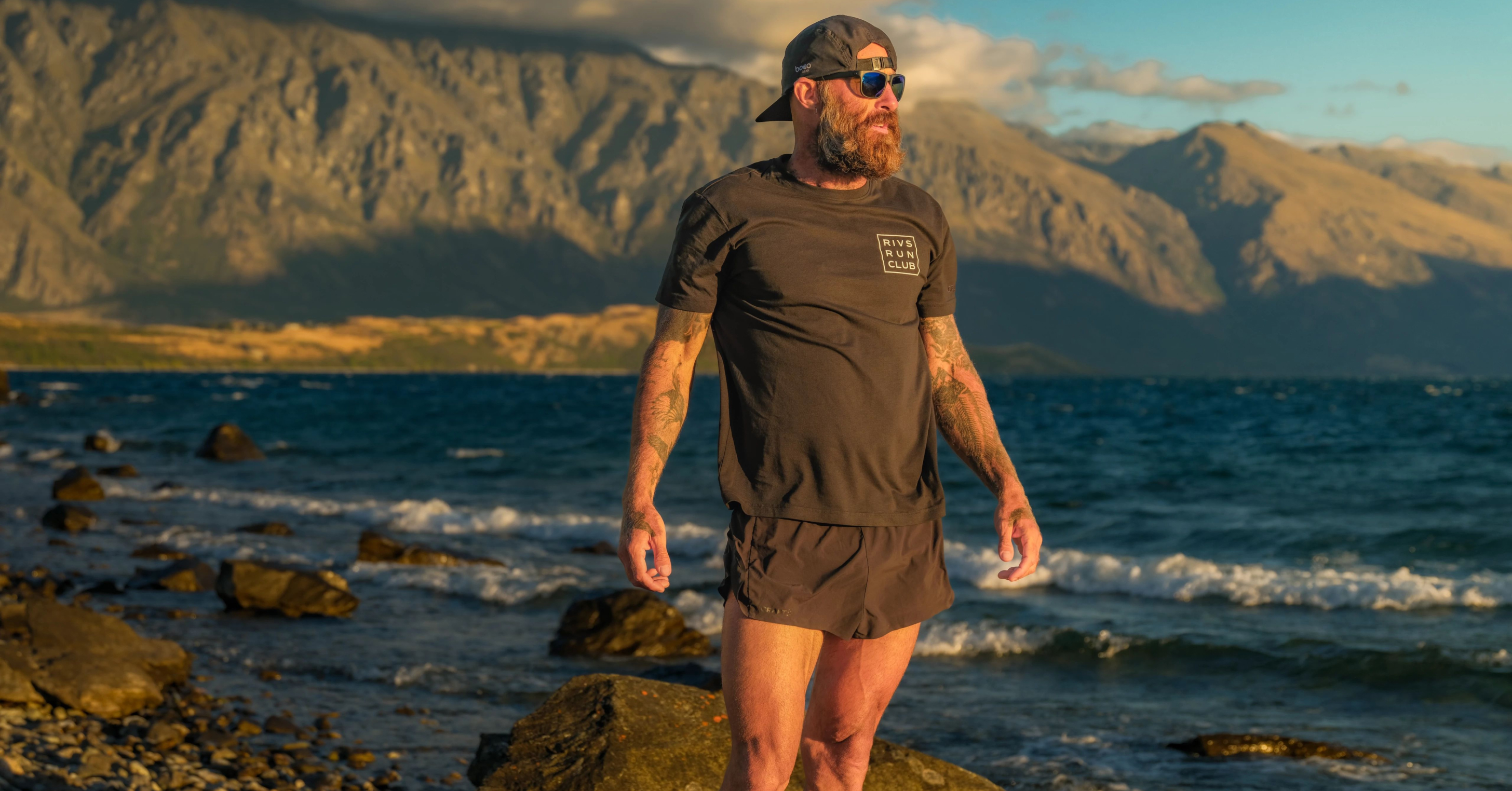 Tommy Rivs stands on the shores of a glacial lake in New Zealand's South Island during the New Zealand season of Rivs Run Club on iFIT.