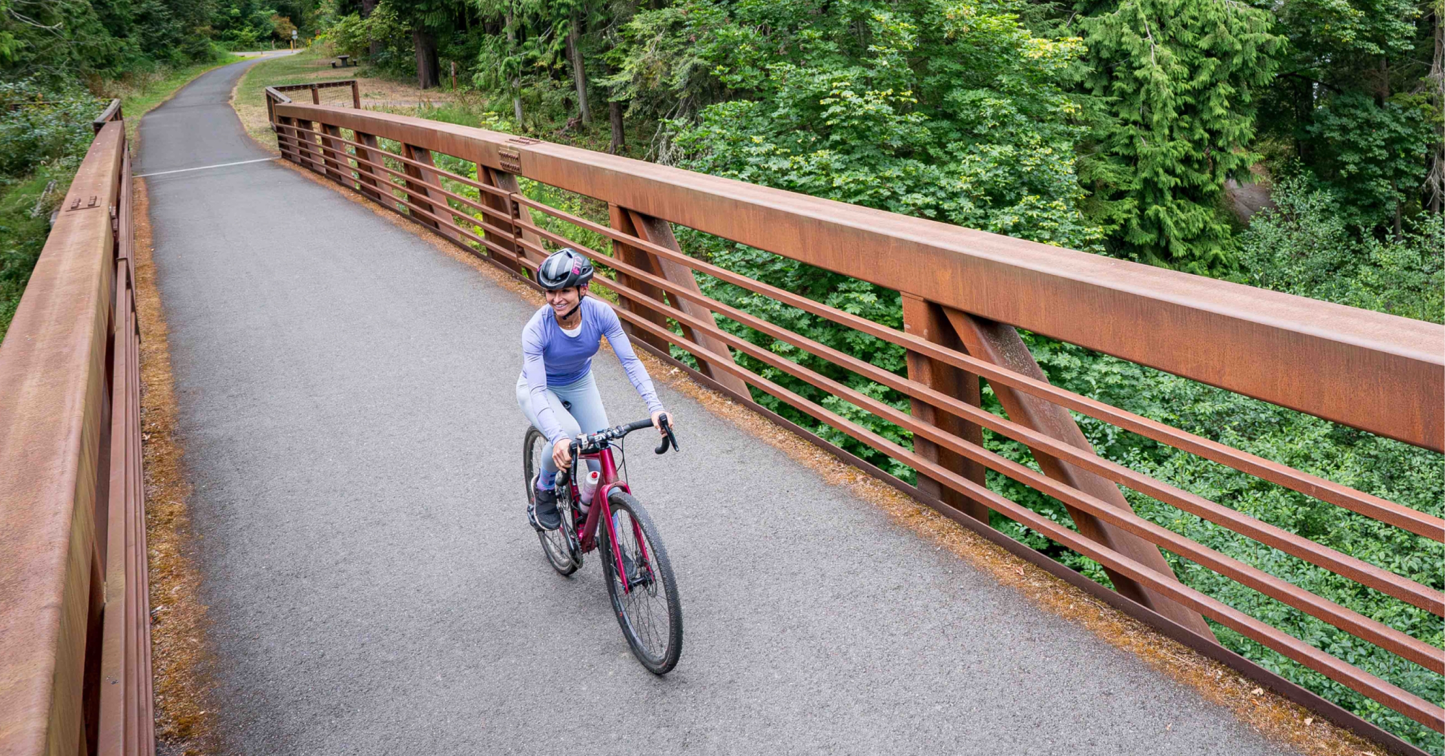 Cyclist riding across a forest bridge during a feel-good iFIT cycling workout