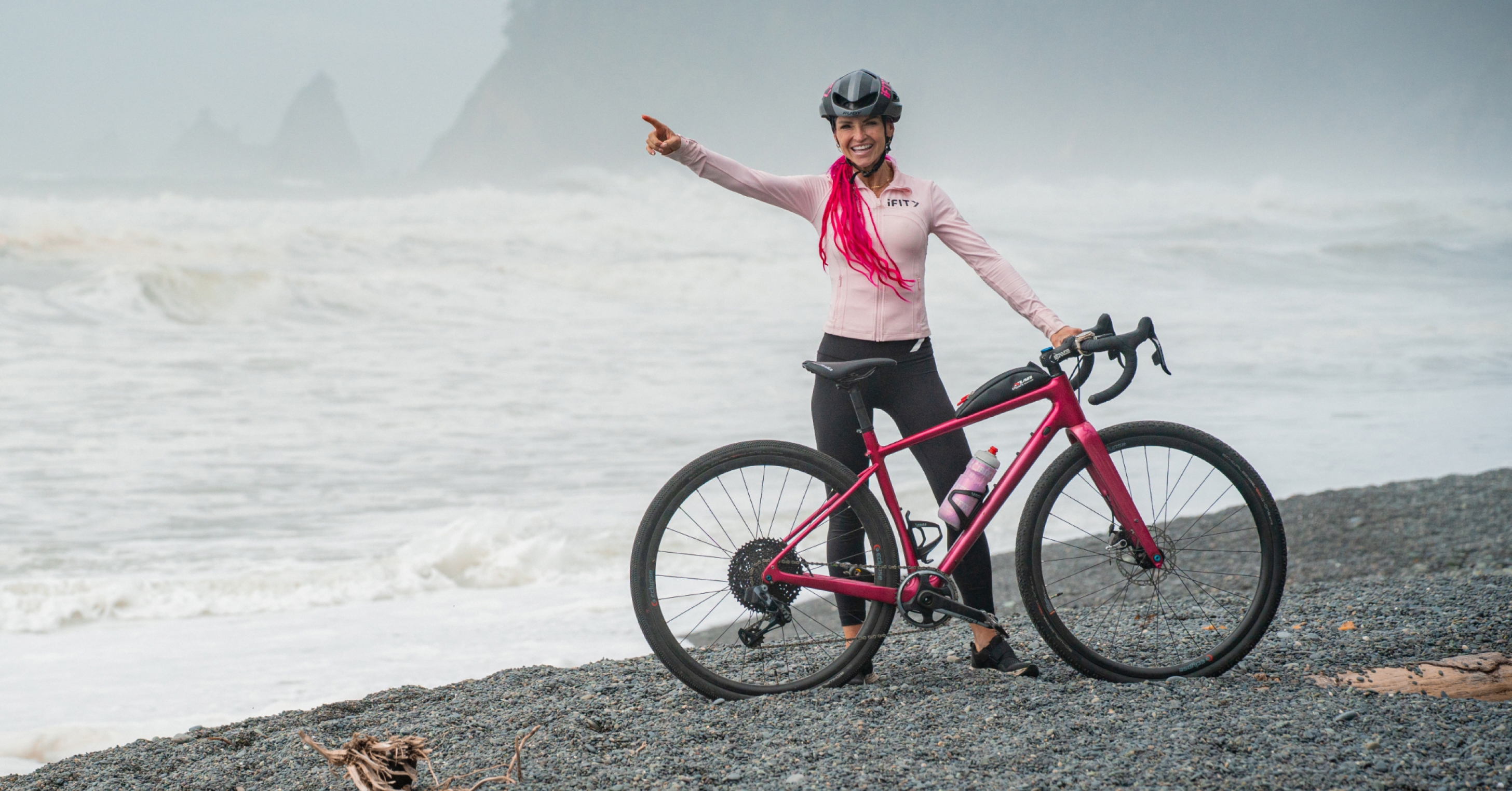 iFIT Trainer Ashley Paulson standing with her bike along the Olympic National Park coastline