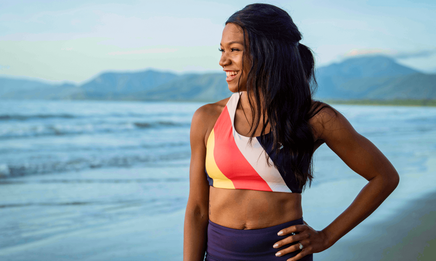 iFIT Trainer Shannon Cooper smiles while looking out on the ocean from an Australian beach.