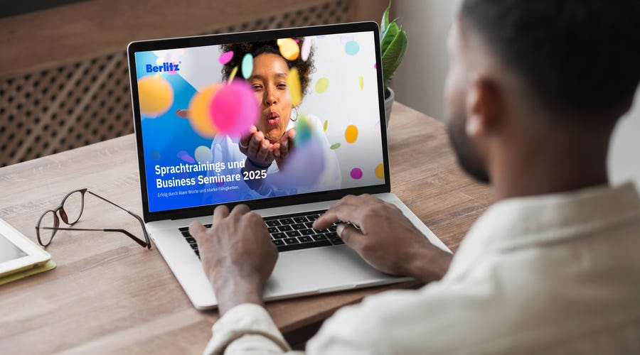 Mann sitzt am Computer und liest Berlitz Katalog.