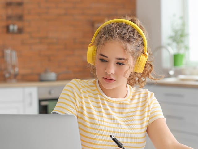 Ein Mädchen mit gelbem Headset sitzt vor einem Laptop und nimmt an einem Online Sprachkurs teil.