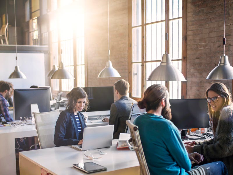 Personen sitzen in einem großen Büro und unterhalten sich