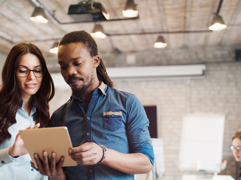 Ein Mann und eine Frau schauen in einem Büro gemeinsam auf ein Blatt Papier.