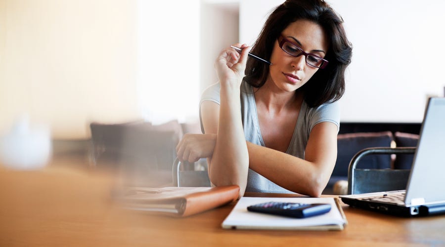 Eien Frau sitzt an ihrem Laptop und schreibt eine Liste.