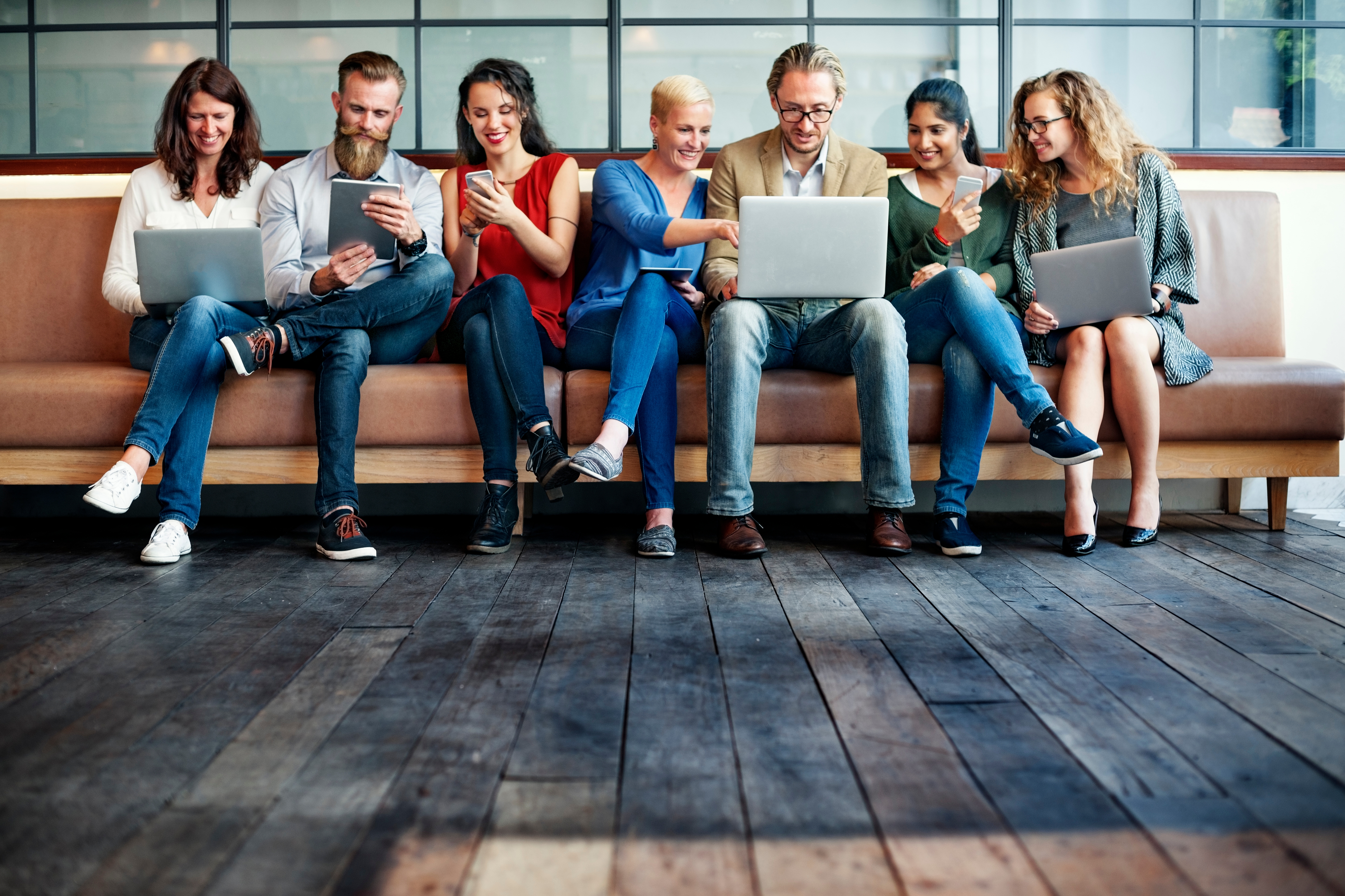 Mehrere Menschen sitzen gemeinsam auf einer Couch und unterhalten sich.