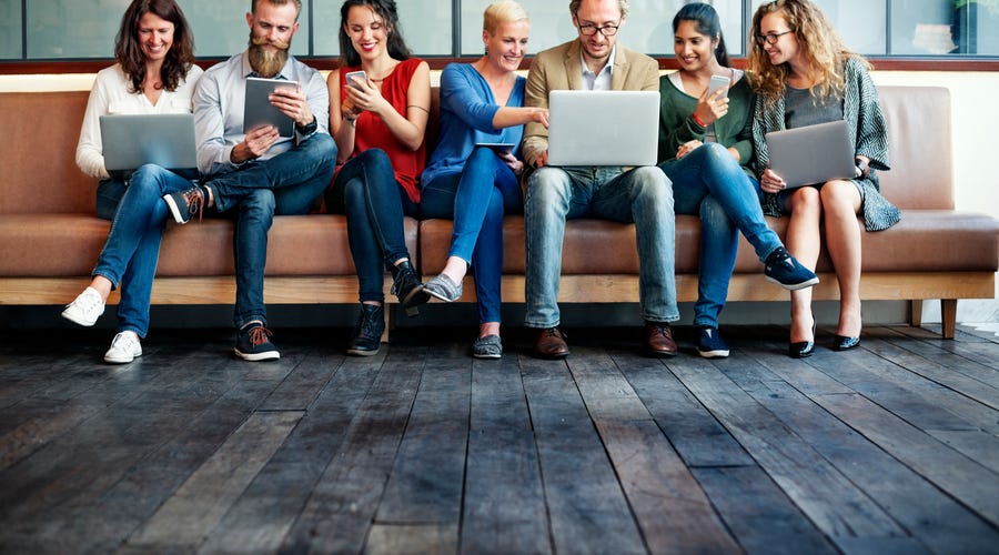 Mehrere Menschen sitzen gemeinsam auf einer Couch und unterhalten sich.