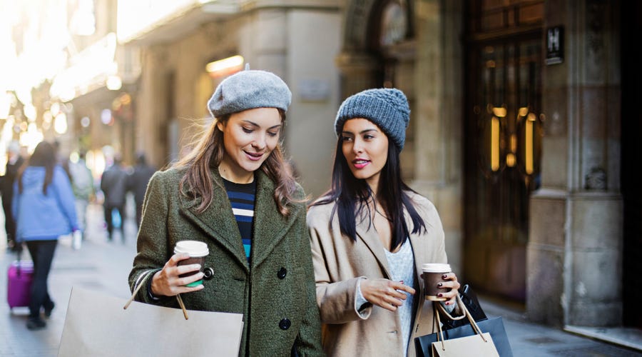 Zwei Frauen laufen durch die Straße und unterhalten sich.
Two women walking in the street and talking.