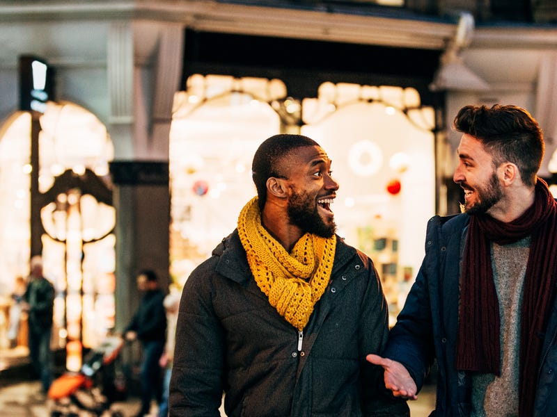 Two men walking and talking in a street.
Zwei Männer laufen durch die Straße und unterhalten sich.