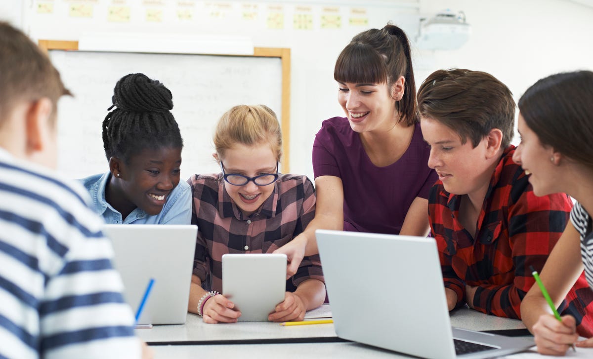 Mehrere Jugendliche sitzen mit einer Trainerin vor ihren Laptops und besprechen eine Aufgabe aus dem Programmierkurs.
