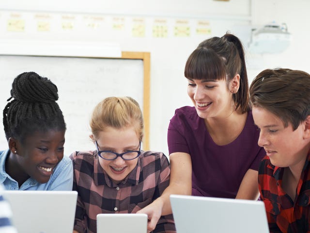 Mehrere Jugendliche sitzen mit einer Trainerin vor ihren Laptops und besprechen eine Aufgabe aus dem Programmierkurs.