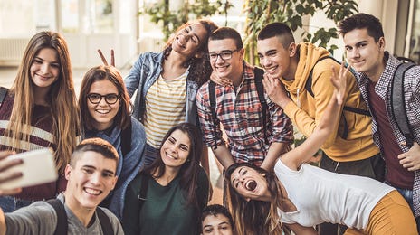 Eine Gruppe von Schülerinnen und Schülern schauen ins Smartphone für ein gemeinsames Foto.