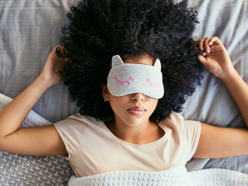 Frau liegt mit Schlafmaske im Bett