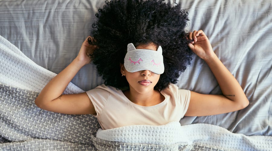 Frau liegt mit Schlafmaske im Bett