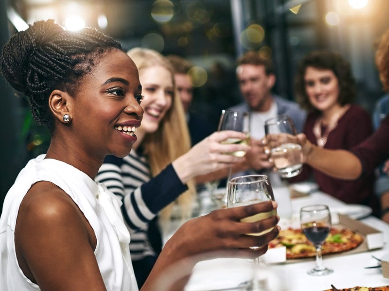 Mehrere Menschen sitzen zusammen am Tisch, trinken und reden.