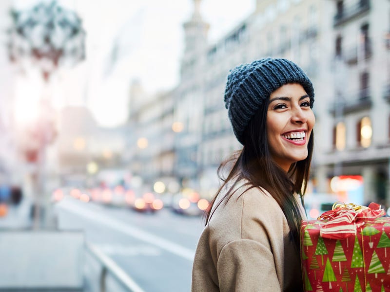 Eine Frau läuft mit einem Geschenk über die Straße