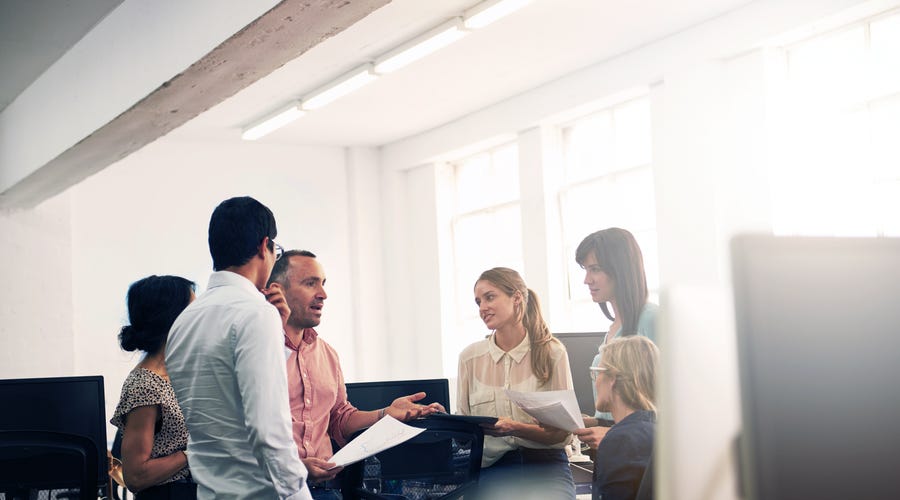 Eine Gruppe von Personen steht in einem Büro zusammen und diskutiert.