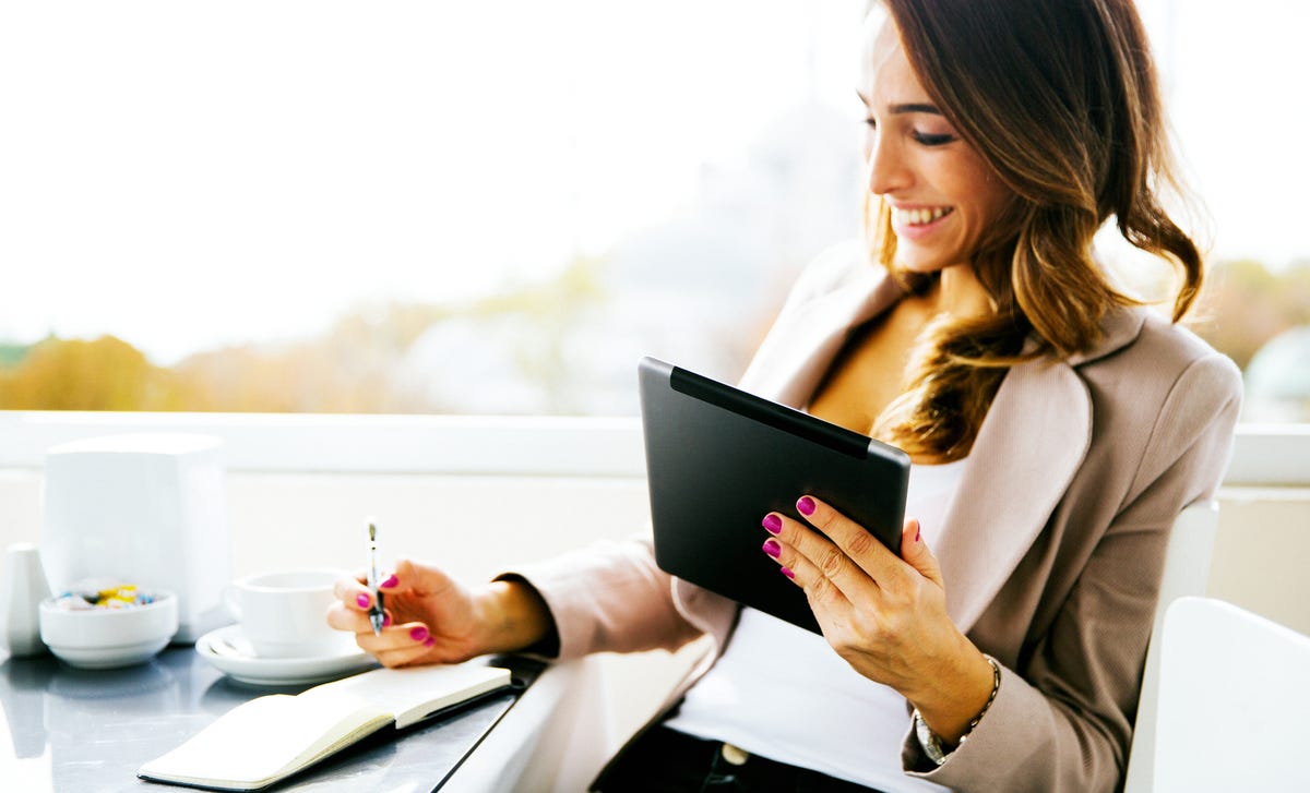 Eine Rechtshänderin macht sich Notizen, während sie ihrem Online-Italienischkurs folgt.