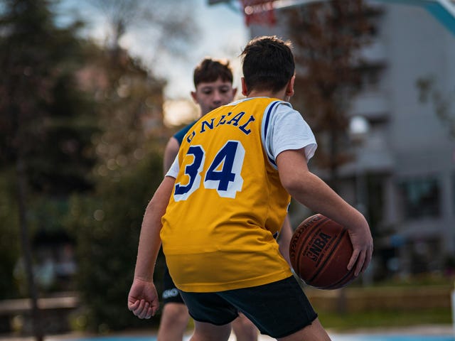 Zwei Jugendliche im Sprachcamp spielen Basketball auf dem Sportplatz.