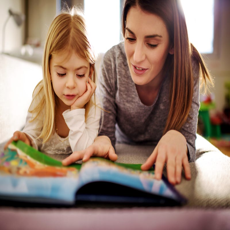 Frau liest Kind aus Märchenbuch vor.