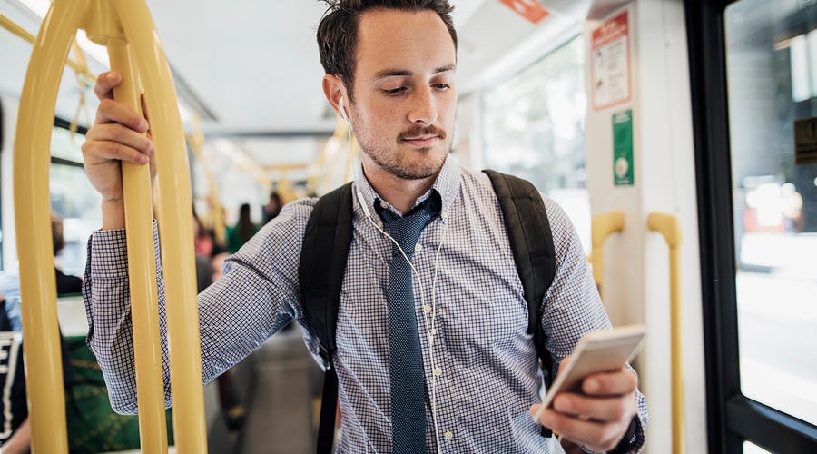 Mann steht mit Smartphone im Bus.