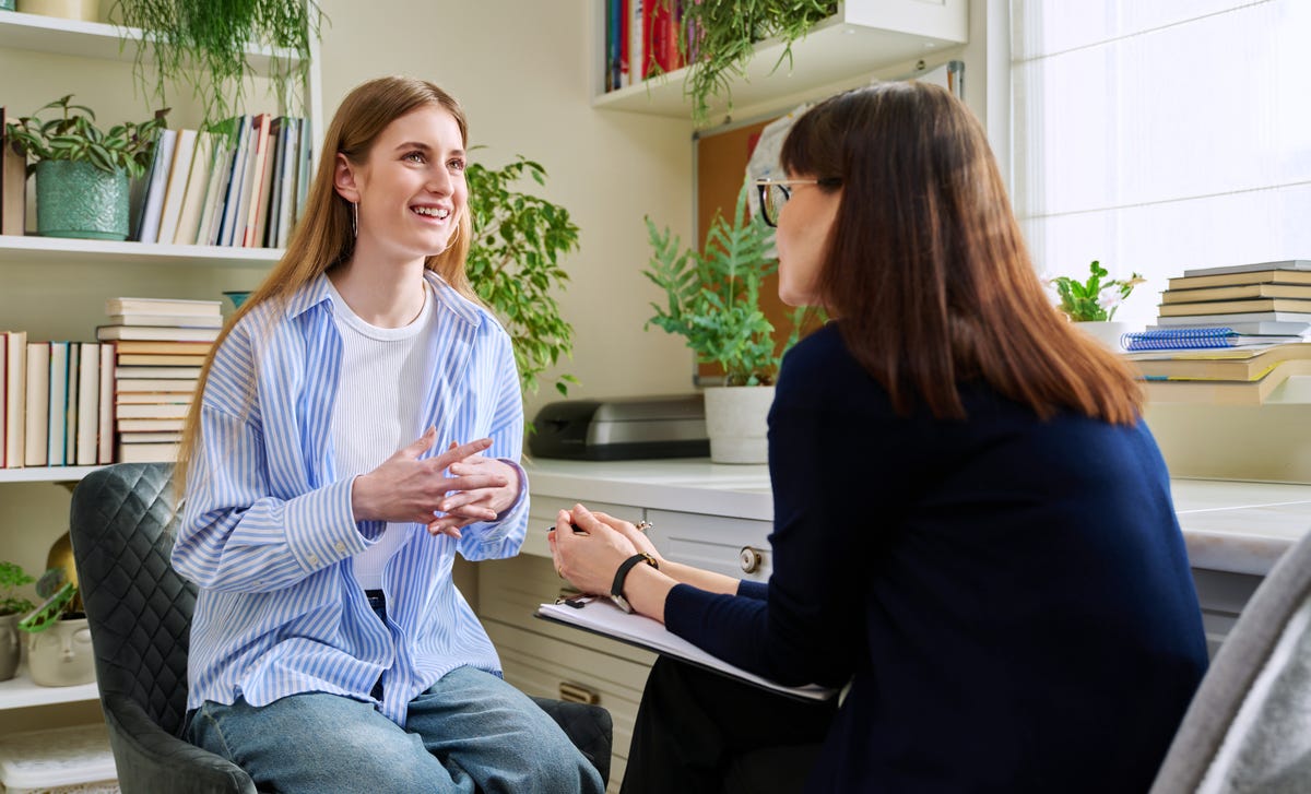 Ein Mädchen sitzt im Sprachkurs mit ihrer Trainerin und unterhält sich.