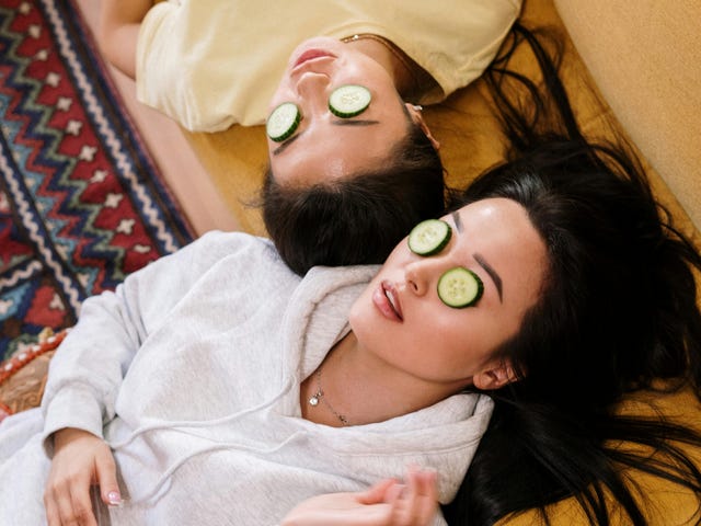 Zwei Mädchen liegen mit Gurkenscheiben auf den Augen im Sprachcamp auf der Couch und unterhalten sich.