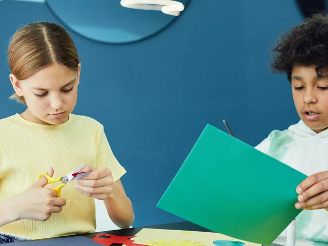 Zwei Kinder im Sprachcamp basteln mit Papier und Schere in einem kreativen Workshop.