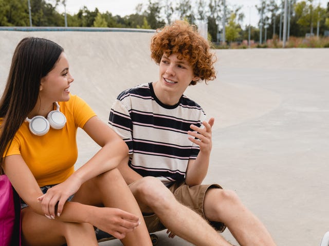 Zwei Jugendliche sitzen draußen im Skatepark zusammen und unterhalten sich über ihren Sprachkurs.