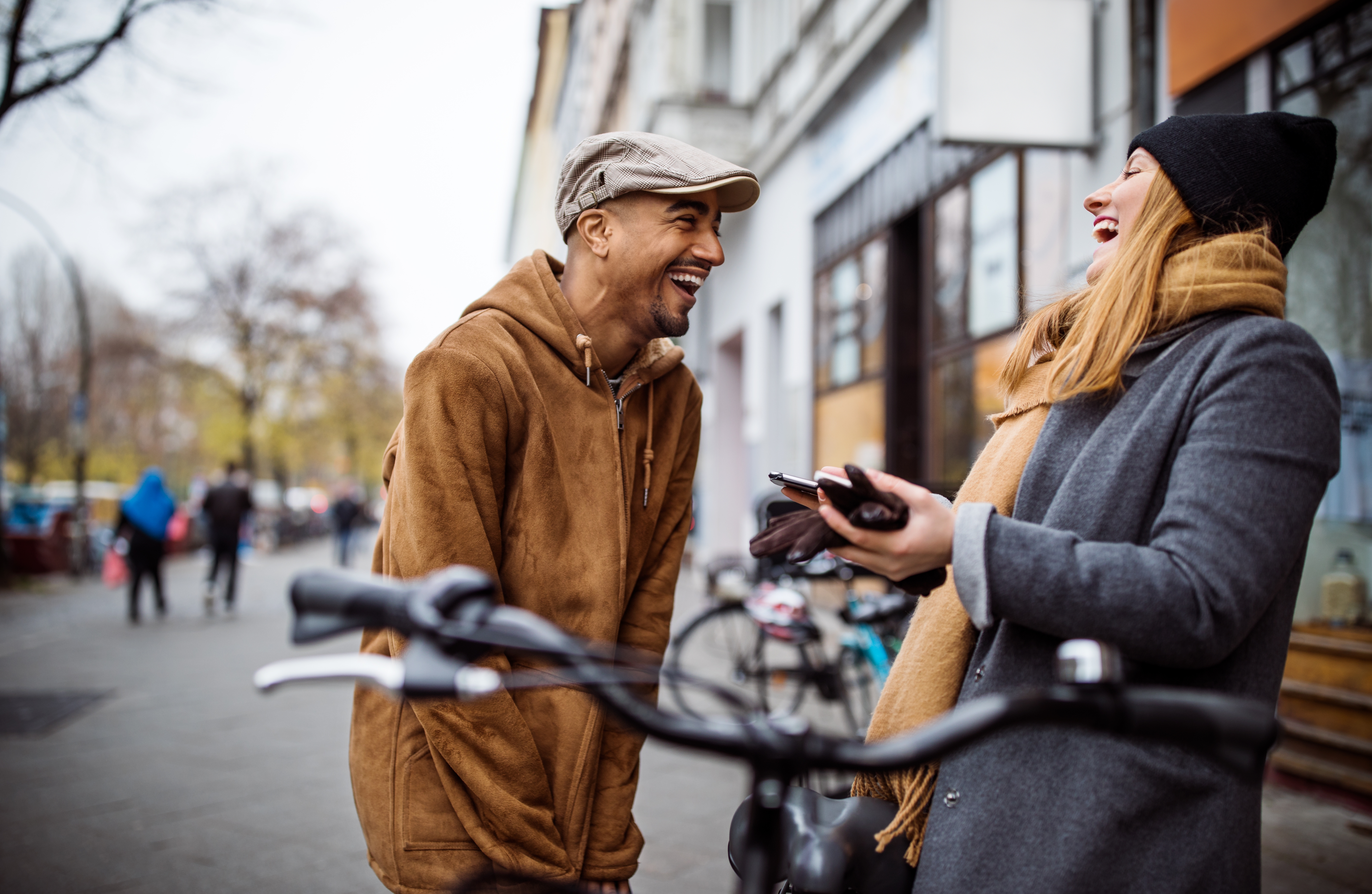 Ein Mann und eine Frau stehen sich auf der Straße gegenüber und lachen.