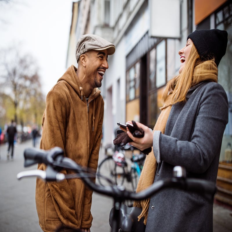 Ein Mann und eine Frau stehen sich auf der Straße gegenüber und lachen.