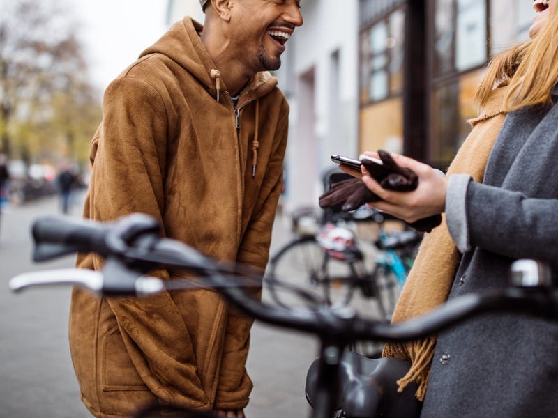 Ein Mann und eine Frau stehen sich auf der Straße gegenüber und lachen.