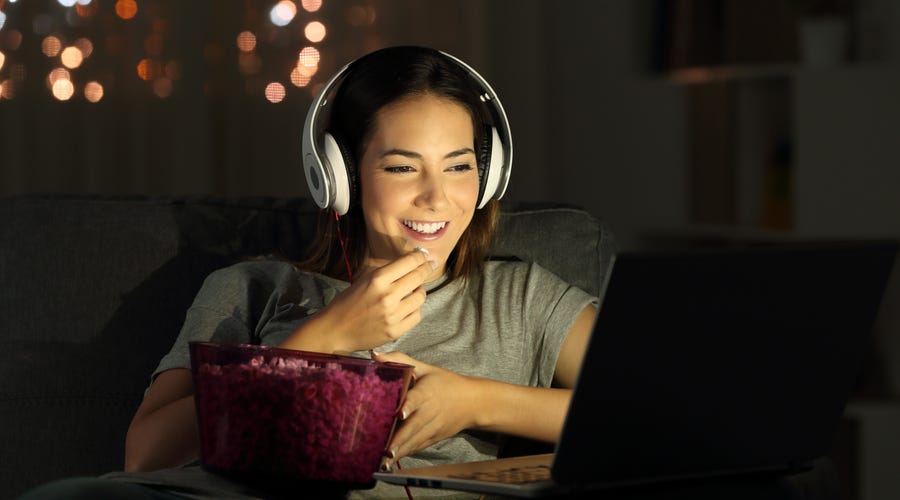 Frau schaut am Laptop eine Serie mit Kopfhörern