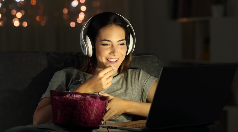 Frau schaut am Laptop eine Serie mit Kopfhörern