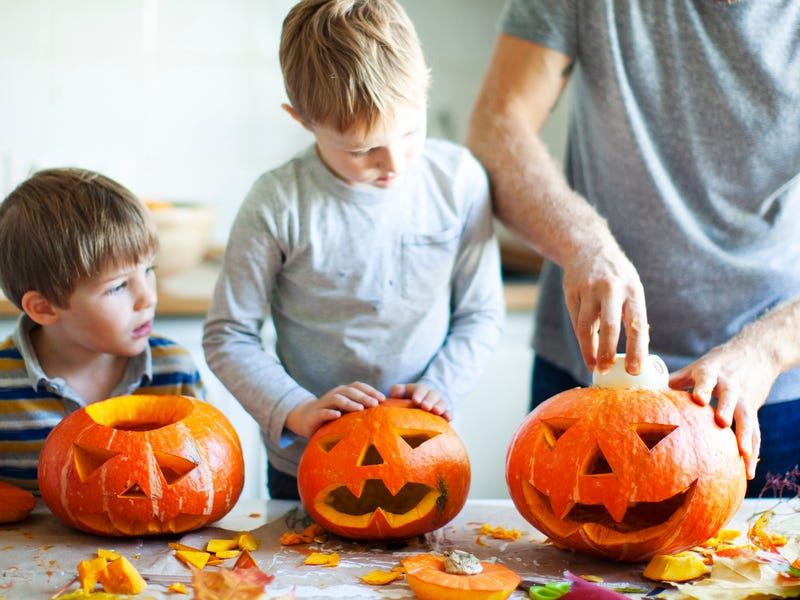 Vater bereitet mit Kindern Halloween-Kürbisse vor