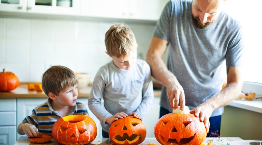 Vater bereitet mit Kindern Halloween-Kürbisse vor