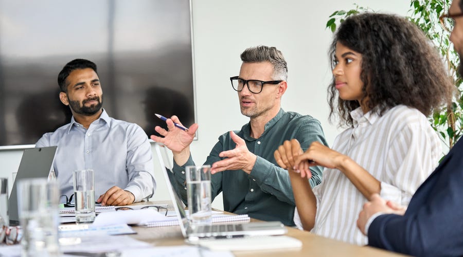 Bildausschnitt von 3 Personen, 2 Männern und einer Frau, am Besprechungstisch.