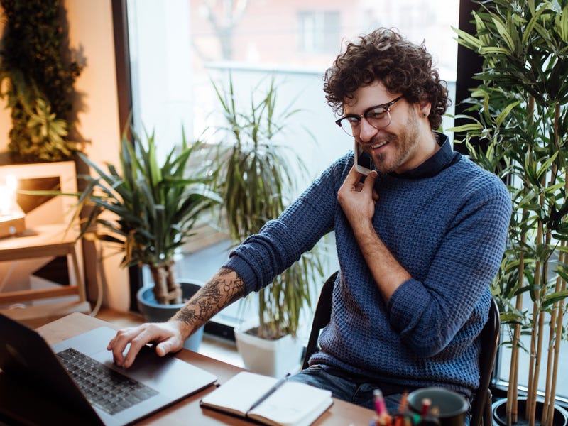 Mann arbeitet am Laptop und telefoniert gleichzeitig.