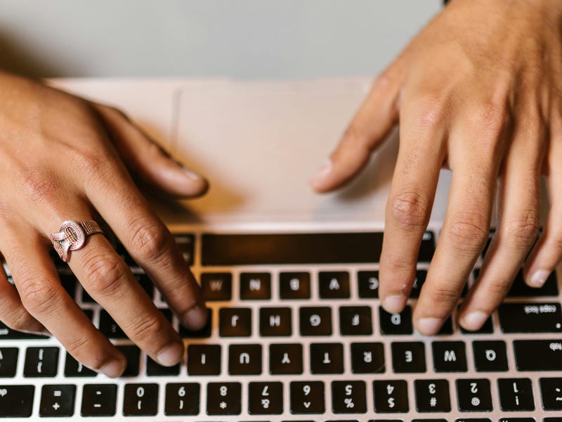 Hände, die auf einer Laptop-Tastatur schreiben.
