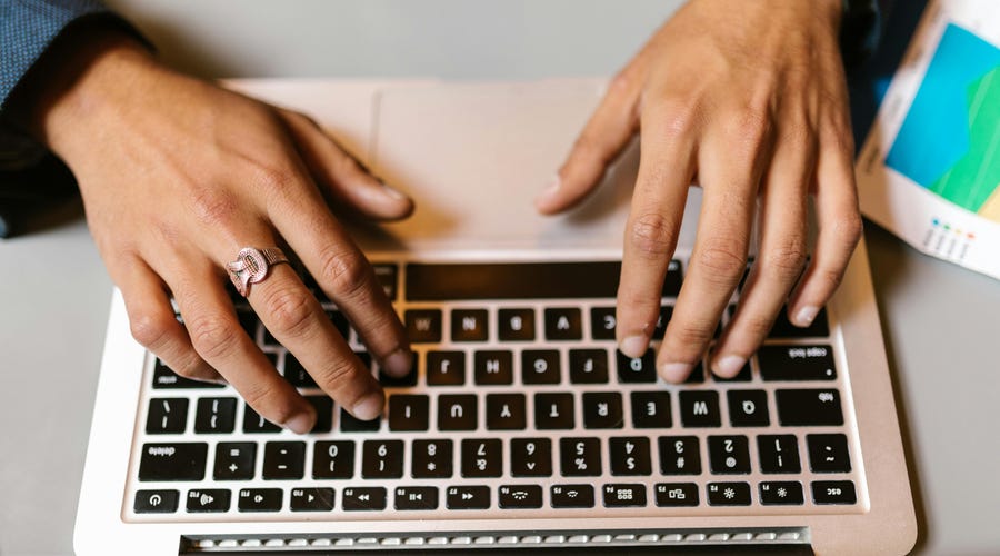 Hände, die auf einer Laptop-Tastatur schreiben.