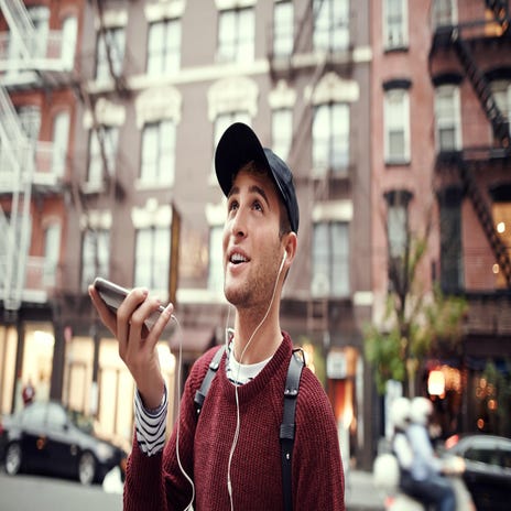 Ein junger Mann mit einer Mütze telefoniert auf der Straße.