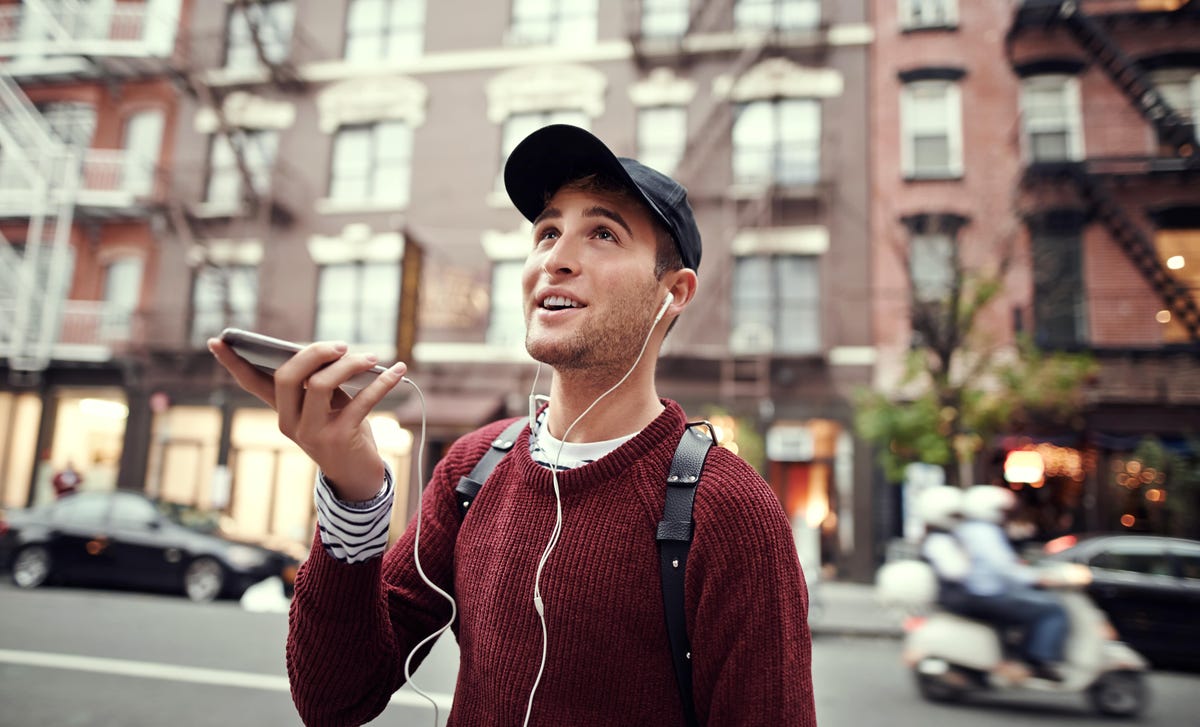 Ein junger Mann mit einer Mütze telefoniert auf der Straße.