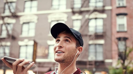 Ein junger Mann mit einer Mütze telefoniert auf der Straße.