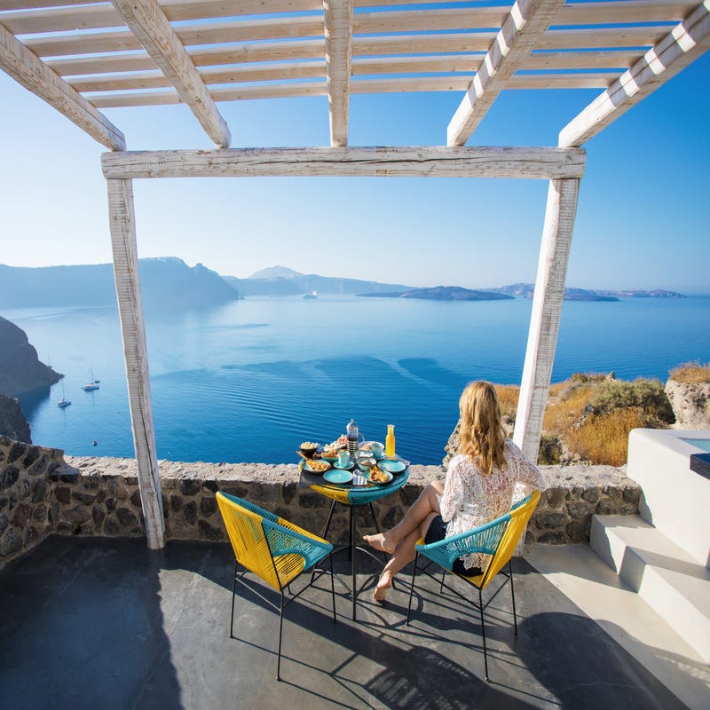 Frau sitzt auf Balkon und blickt Richtung Meer