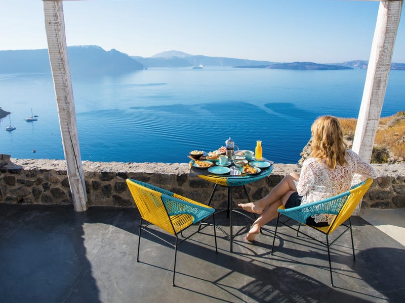 Frau sitzt auf Balkon und blickt Richtung Meer