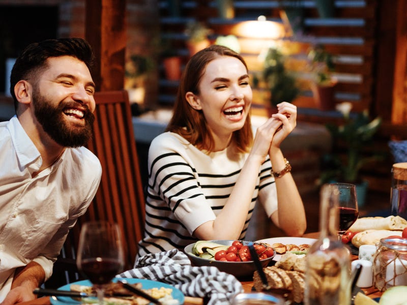 Paar sitzt am Essenstisch und lacht.